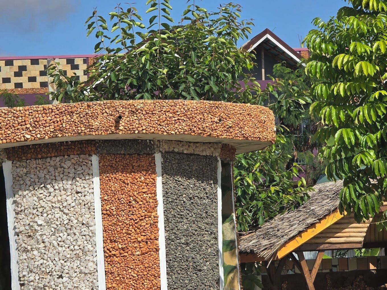 A structure with a curved roof, surrounded by a variety of plants and trees.