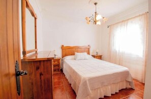 A bedroom with a wooden bed, a nightstand, a mirror, and a chandelier.