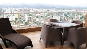 A balcony with wicker furniture and a city view. - Cobertura de Alto Padrão • Cyrela • Boqueirão (Santos)