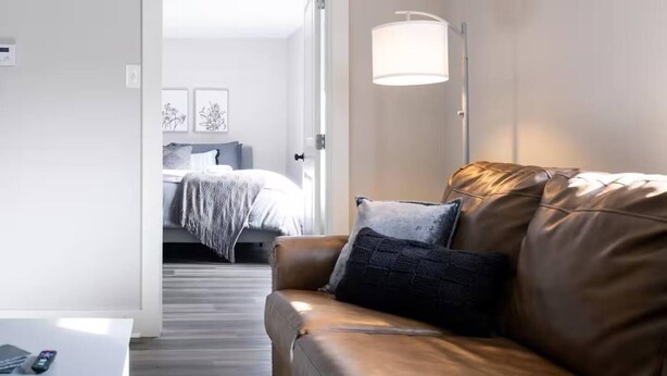 En moderne stue med en lædersofa, et sengebord og en lampe.