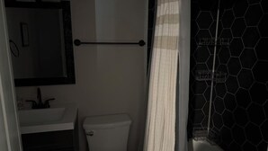 Et badeværelse med toilet, vask og bruseforhæng.