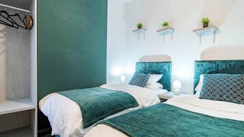 A bedroom with two beds, a closet, and wall-mounted shelves with plants.