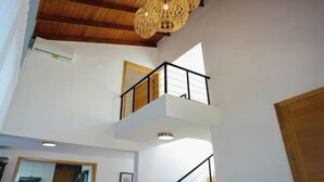 A multi-level interior with a wooden ceiling, a balcony with a railing, and a hanging light fixture. - A Casa do Lago: comfort, nature and unforgettable moments on the shore of the water (Romana)