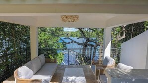 A covered outdoor seating area with a sofa and chairs, overlooking a body of water and trees. - A Casa do Lago: comfort, nature and unforgettable moments on the shore of the water (Romana)
