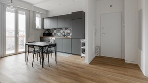 A modern kitchen with grey cabinets, a black countertop, and a white dining table with chairs. - Casa Amarenzi by Wonderful Italy (Bologna)