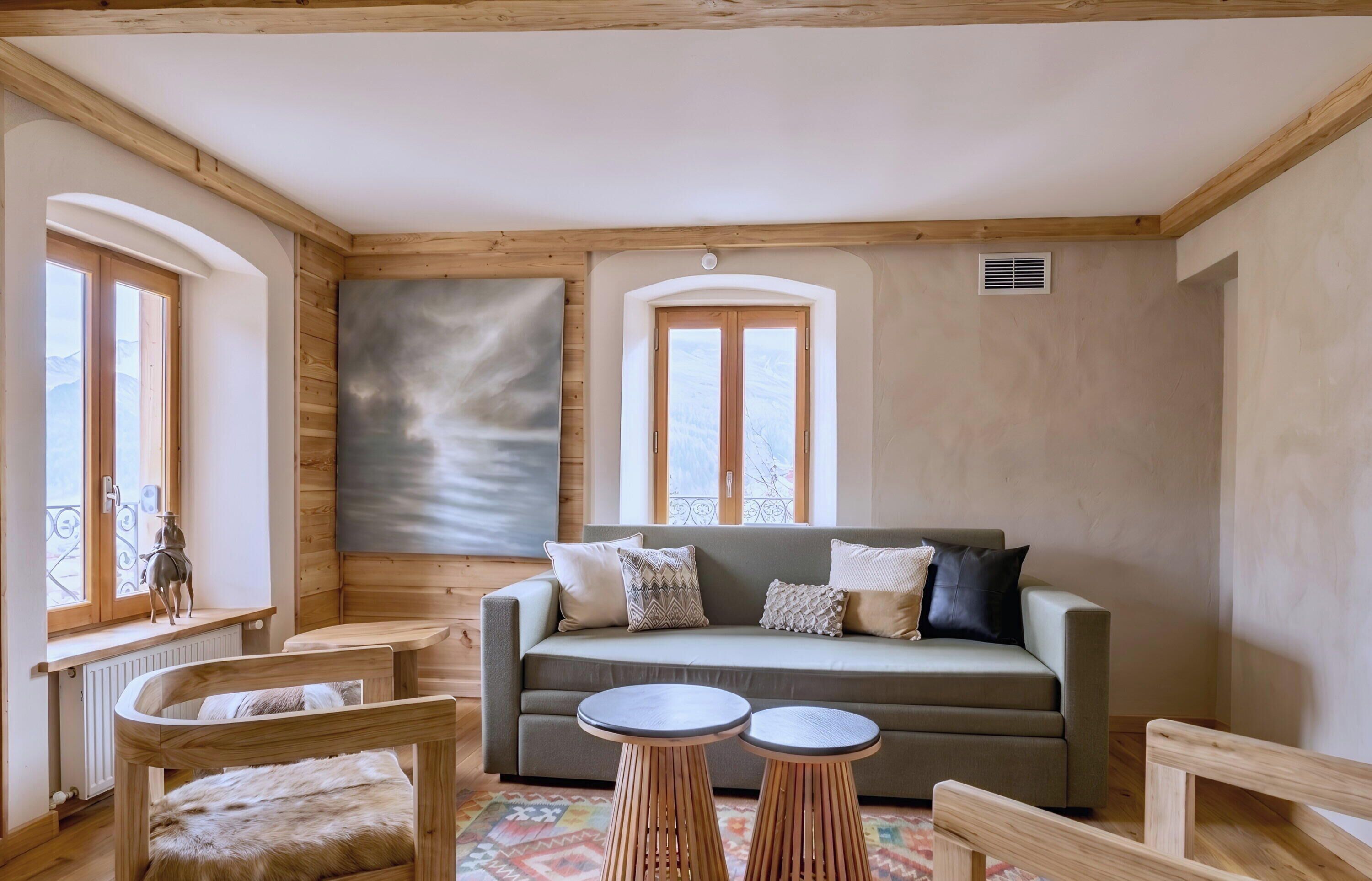 A cozy room with a wooden ceiling, a sofa with cushions, a small round table, and a radiator.