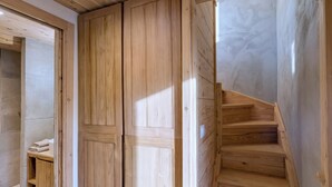 A wooden staircase leading to a room with a wardrobe and a shelf with towels. - CASA-Niu Luxe discret, vue et pied des pistes (Molines-en-Queyras)