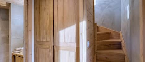 Een houten trap die leidt naar een kamer met een kast en een plank met handdoeken.