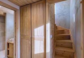 Eine Holztreppe führt zu einem Raum mit einem Kleiderschrank und einem Regal mit Handtüchern.
