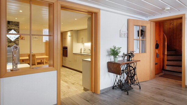 A modern interior with wooden flooring, a dining area, a kitchen, and a staircase.