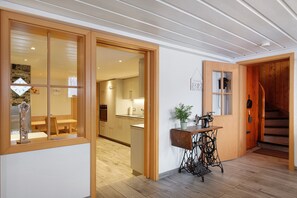 Un interior moderno con suelo de madera, zona de comedor, cocina y escalera.