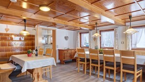 A wooden dining area with a table and chairs, a wooden cabinet, and a ceiling with wooden beams.