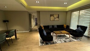 A modern living room with a sofa set, a coffee table, and a dining area with chairs and a table. - Peravi Suites at Pearl In The City (Accra)