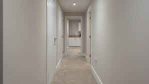 A narrow hallway with white walls and carpet leading to a kitchen area. - Chic 1Bed in Hull City Centre near Hull College (Hull)