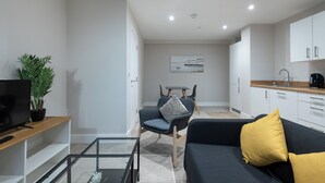 A modern living room with a sofa, a coffee table, a TV, and a plant. - Chic 1Bed in Hull City Centre near Hull College (Hull)