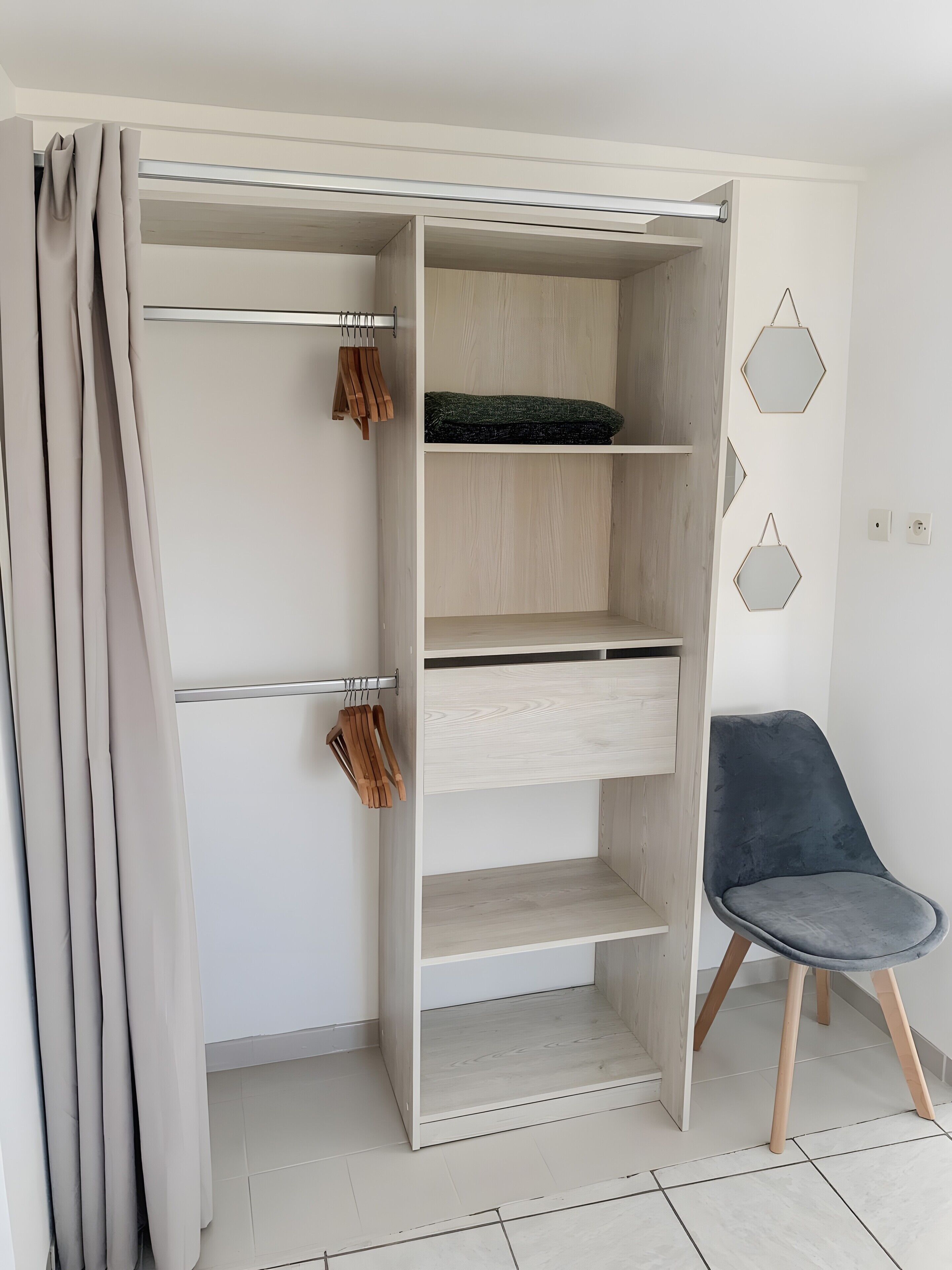 Um closet amplo com portas abertas, prateleiras de madeira e espaço para pendurar roupas.