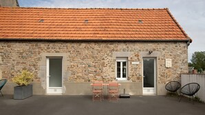 A stone building with a tiled roof, two doors, a small window, and a potted plant. - Holiday Home “Escapade Pirouaise - L'Oyat” with Terrace, Garden and Wi-Fi (Pirou)