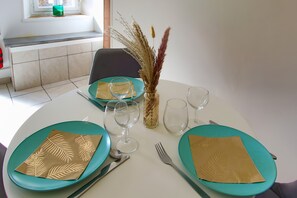 Une table à manger dressée avec des assiettes turquoise, des serviettes dorées et des verres à vin transparents.