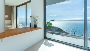 Een moderne kamer met een groot raam met uitzicht op de kust.