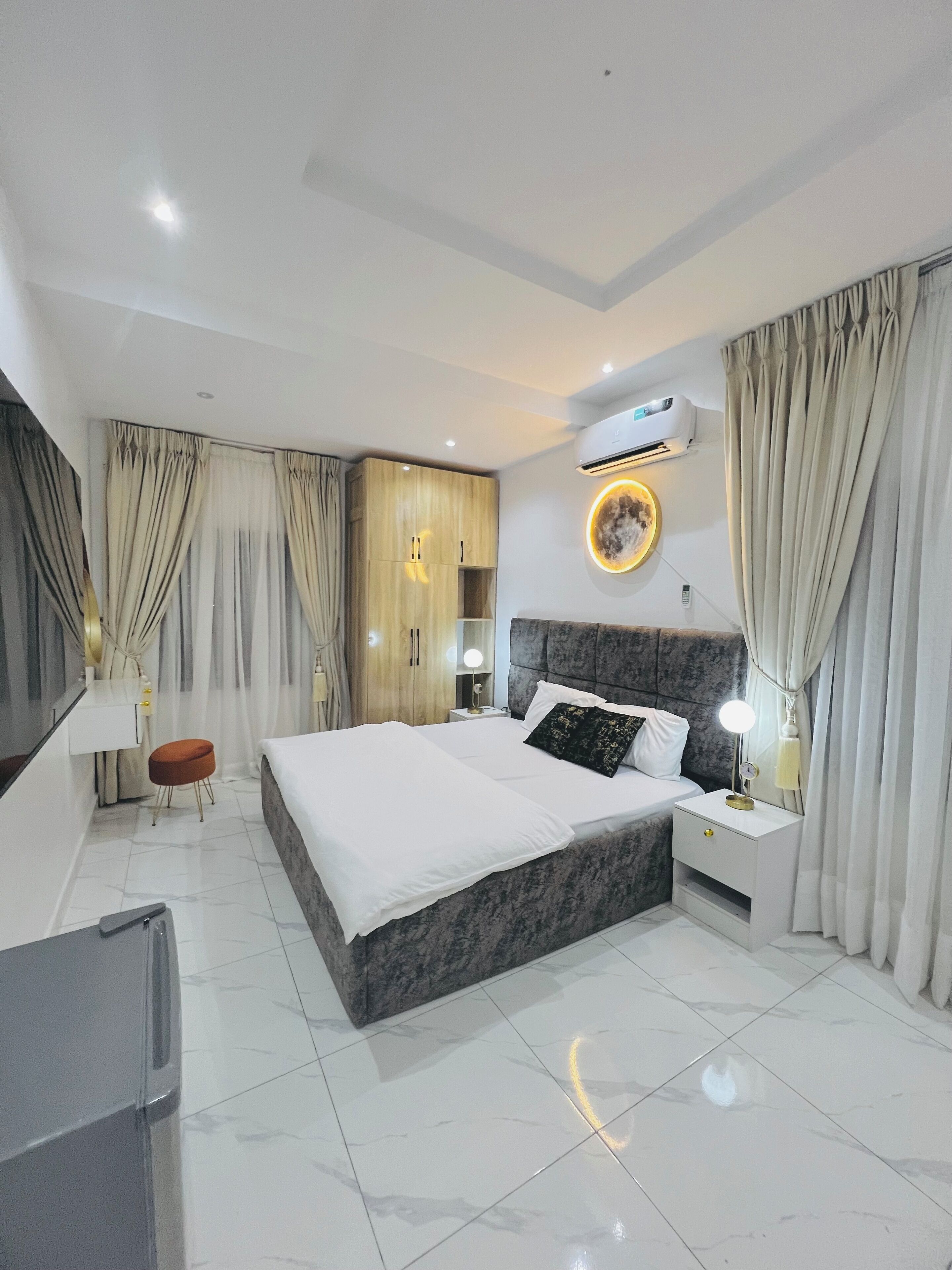 Quarto de hotel moderno com uma cama grande, uma mesa de toucador com espelho e um aparelho de ar condicionado na parede.
