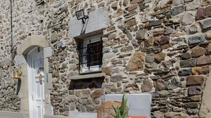 A stone wall, a white door, a table with chairs, and a potted plant. - Seaside Cottage - Le Coquelicot (Pirou)