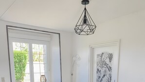 A modern living room with a grey sofa, a wicker chair, and a small round table. - Seaside Cottage - Le Coquelicot (Pirou)