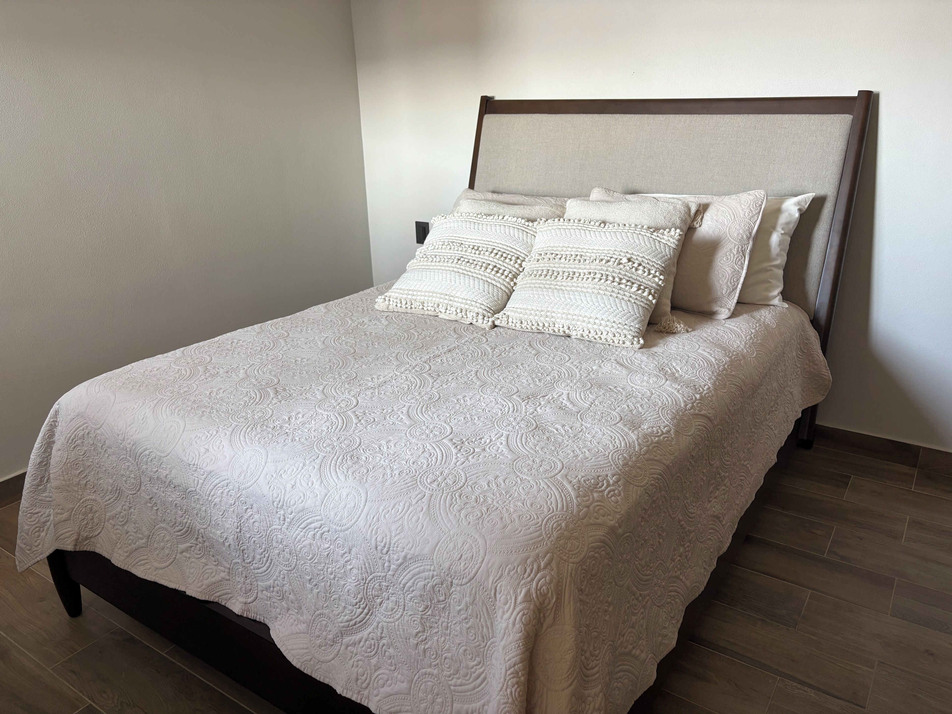A neatly made bed with a patterned bedspread and two decorative pillows.
