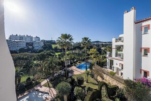 A residential area with a swimming pool, palm trees, and a view of a hill. - 92 - Apartment With Beautiful Views and Pool in Miraflores, Mijas (Las Lagunas de Mijas)