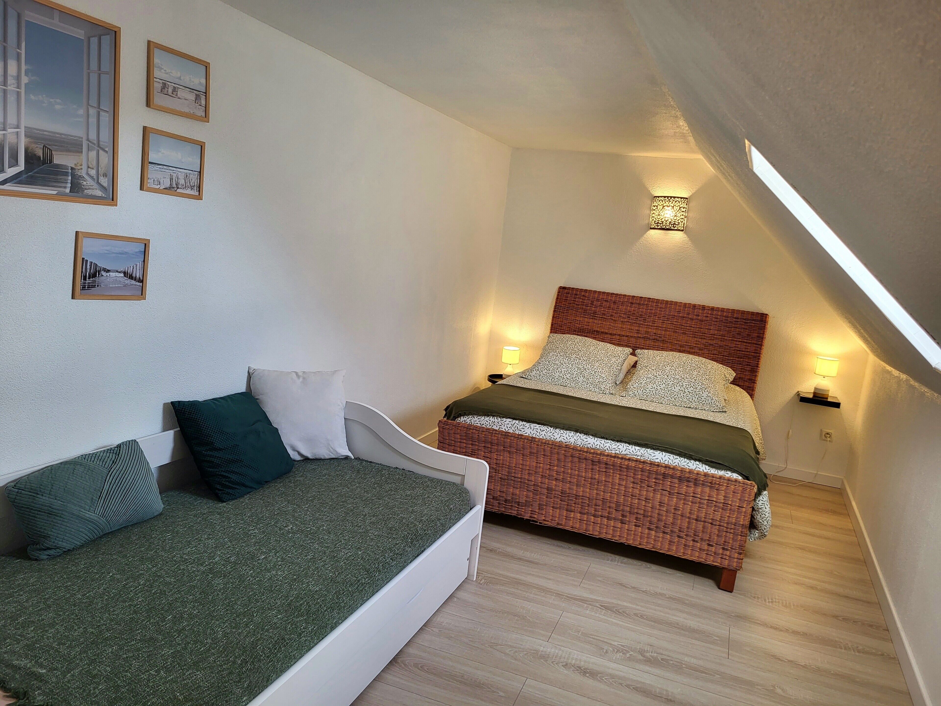 A bedroom with a bed, a sofa, and wall-mounted lights.