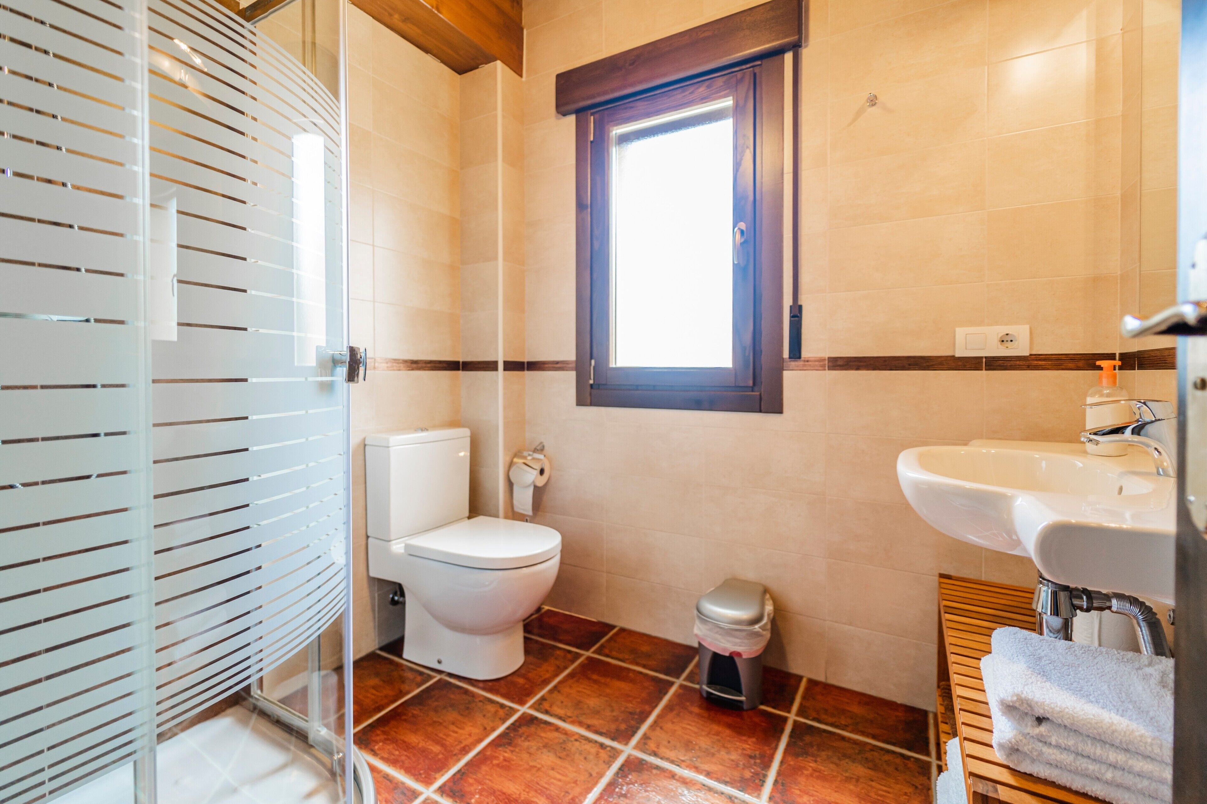 Un baño con inodoro, lavamanos, ventana y zona de ducha.