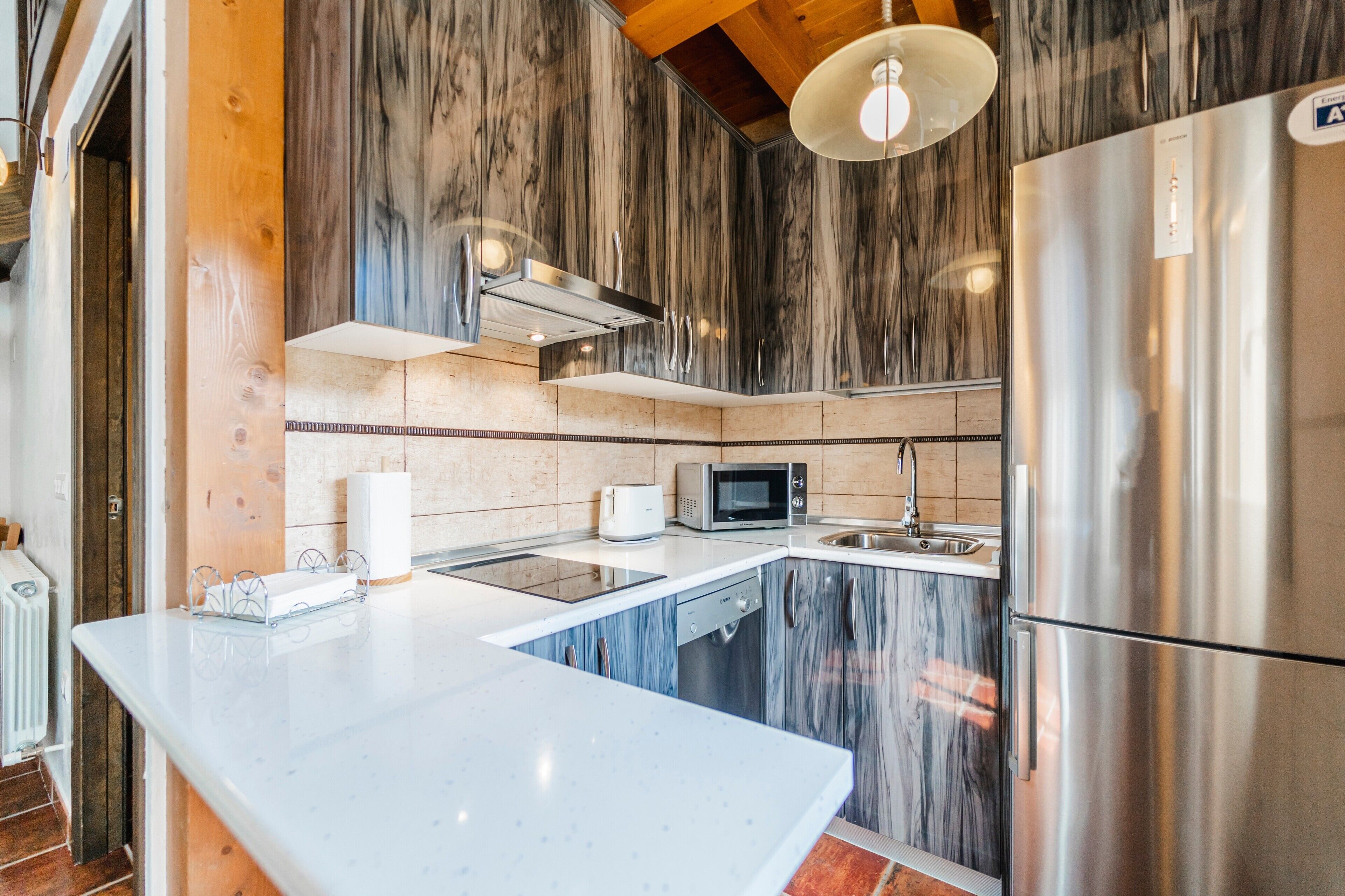 A modern kitchen with a marble backsplash, stainless steel appliances, and a white countertop.