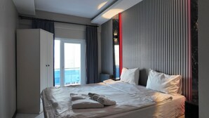 Una camera d'albergo moderna con un letto grande, un armadio e vista mare.