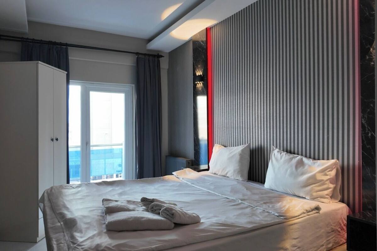 Une chambre d’hôtel moderne avec un grand lit, une armoire et une vue sur la mer.