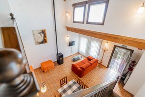 En stue med sofa, bord og fjernsyn. Der er pejs, et vindue og en dør med teksten 'SALIDA'.