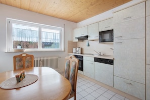 A kitchen with a dining table, chairs, a window, and a microwave.
