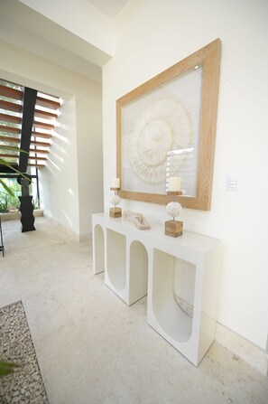 A modern hallway with a white console table, a framed artwork, and a potted plant. - Ceiba 7 (Punta Cana)