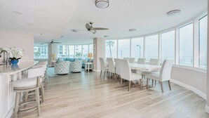 Una cocina amplia con comedor, ventanas grandes y vista al océano.