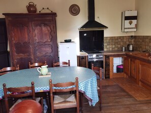 Una cocina con una mesa redonda, sillas, estufa, refrigerador y un mueble.