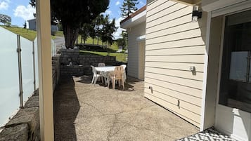 Un patio al aire libre con zona de estar techada, un muro de piedra y vistas a un barrio residencial.
