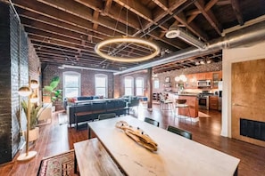 A spacious loft with exposed brick walls, a large dining area, and a kitchen with bar stools. - The Loft on Main, Penthouse Loft near Main Street (Lynchburg)