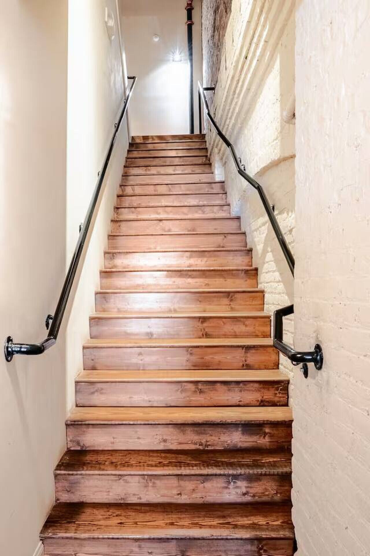 A wooden staircase with metal handrails, leading to an upper floor.