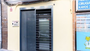 Un edificio con puerta metálica, detector de incendios y un personaje de dibujos animados en una ventana.