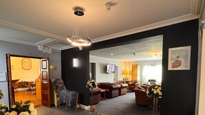 Un moderno vestíbulo de hotel con comedor, mostrador de recepción y un gran ventanal.