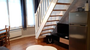 Et moderne køkken med en trætrappe, et køleskab og et spiseområde med et bord og stole.