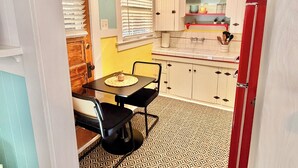 A compact kitchen with a dining table, chairs, and a refrigerator.