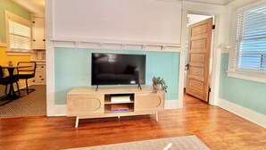A living room with a wooden entertainment center, a flat-screen TV, and a potted plant.