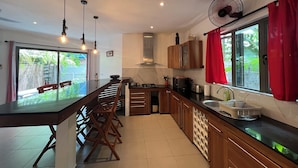 A modern kitchen with a long island, wooden cabinets, and a large window with red curtains. - O Paradis Albion Large swimming pool and the beach just steps away (Albion)