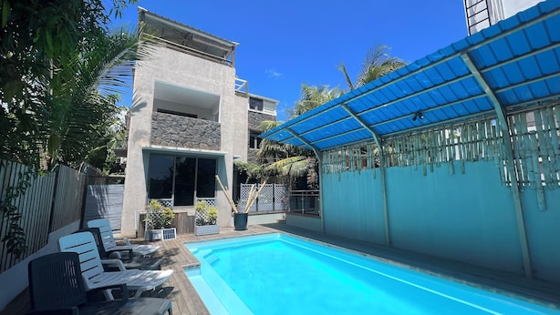 A swimming pool with lounge chairs, a covered patio, and a stone facade building. - O Paradis Albion Large swimming pool and the beach just steps away (Albion)