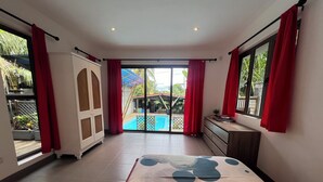 A bedroom with a large bed, a sliding glass door leading to a pool area, a wardrobe, and a small desk. - O Paradis Albion Large swimming pool and the beach just steps away (Albion)
