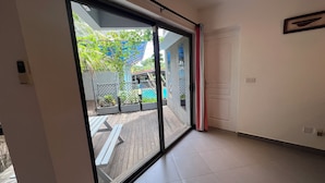 A room with a large sliding glass door leading to an outdoor area with a wooden deck and a pool. - O Paradis Albion Large swimming pool and the beach just steps away (Albion)